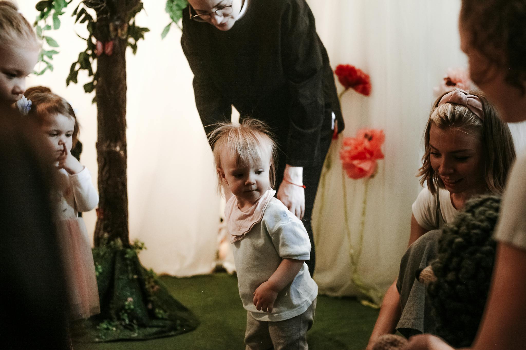 A group of children playing indoors with supervision from adults, enjoying a playful environment.